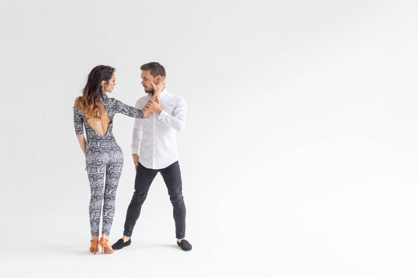 Skillful dancers performing in the white background with copy space. Sensual couple performing an artistic and emotional contemporary dance - Foto, imagen