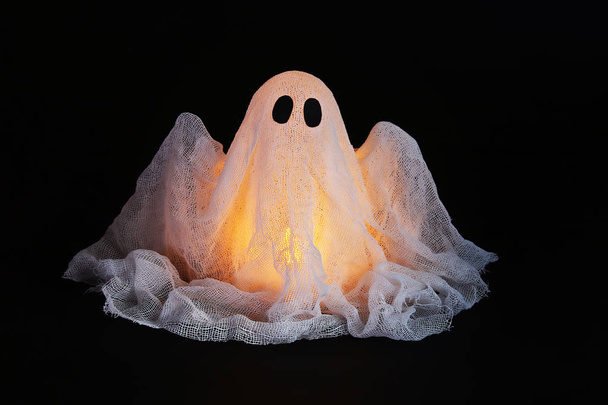 Halloween ghost of starch and gauze on black background. Gift idea, decor Halloween. - Foto, afbeelding