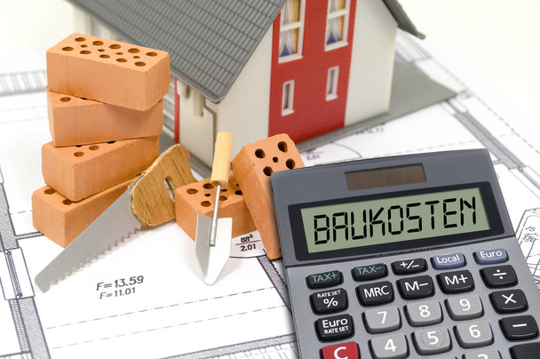 Construction or building plan with bricks and calculator showing the german word for building costs - baukosten - Photo, Image