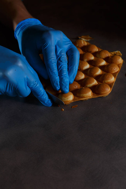 Coocking belgian waffles with two hands in blue gloves on dark tabletop - Photo, Image