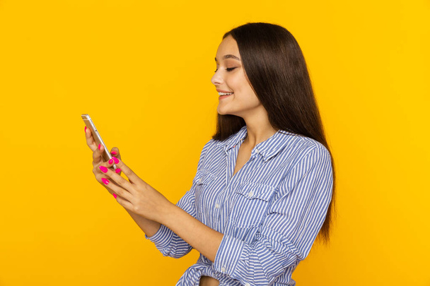 Mujer bonita feliz con lauthing teléfono en el estudio amarillo
. - Foto, Imagen