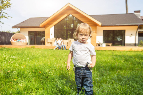 small child stands on the background of the house. young family move to a new country house. moving day. - Photo, image