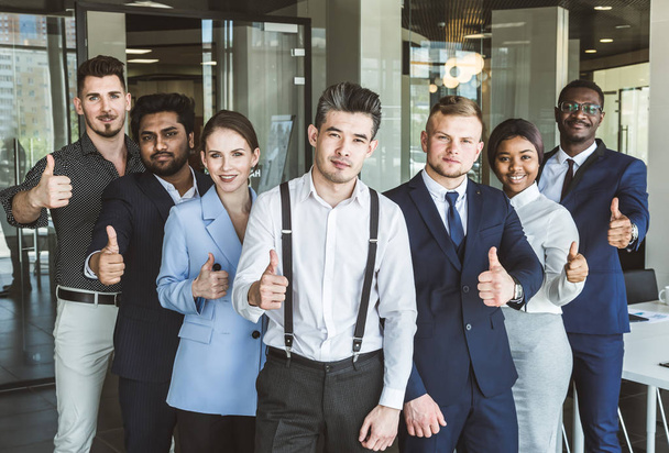 A team of young businessmen stand shoulder to shoulder, working and communicating together in an office. Corporate businessteam and manager in a meeting. - 写真・画像