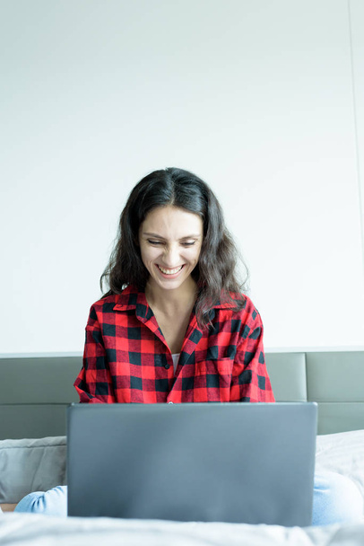 Piękna kobieta pracująca na laptopie z uśmiechem i siedząc na  - Zdjęcie, obraz