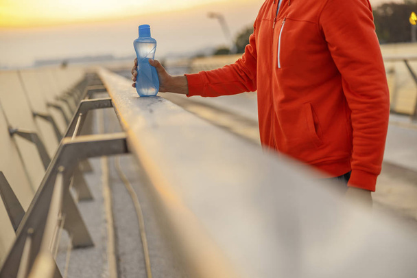 Sportsman with a bottle of water on a bridge - Foto, immagini