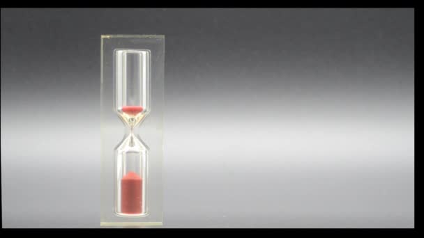 Zandloper met korrels van rood zand dat het verstrijken van de tijd markeert - Video