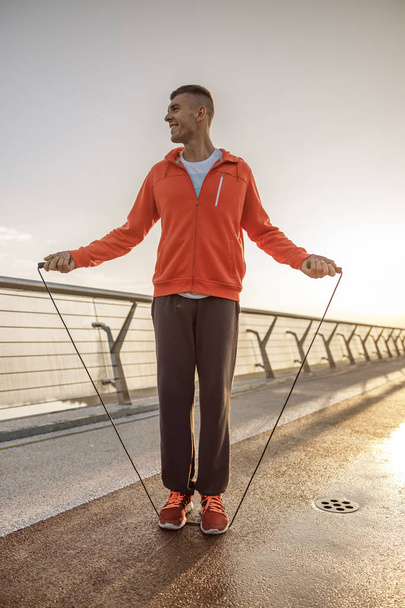 Handsome pleased sportsman working out with a jumping rope - Foto, Imagen