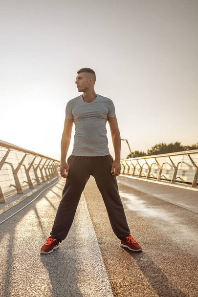 Sportive young man standing on a bridge - Foto, Bild