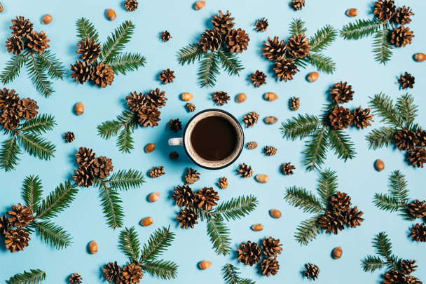 Christmas or winter composition. Frame made of fir tree branches, cup coffee, pine, acorn on pastel blue background. Christmas, winter, new year concept. Flat lay, top view, copy space - 写真・画像
