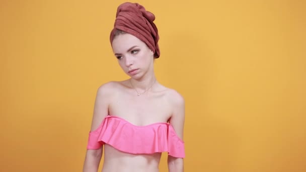jong meisje met handdoek op haar hoofd over geïsoleerde oranje achtergrond toont emoties - Video