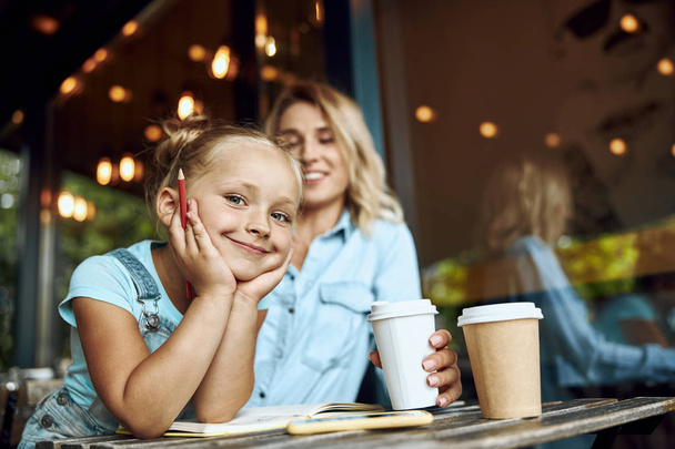 Cute smiling girl in cafe with her mum stock photo - Zdjęcie, obraz