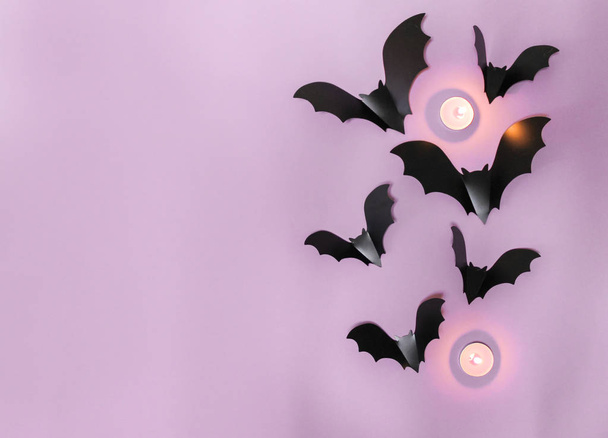 halloween, decoration and scary concept - black bats flying over lilac background - Photo, Image