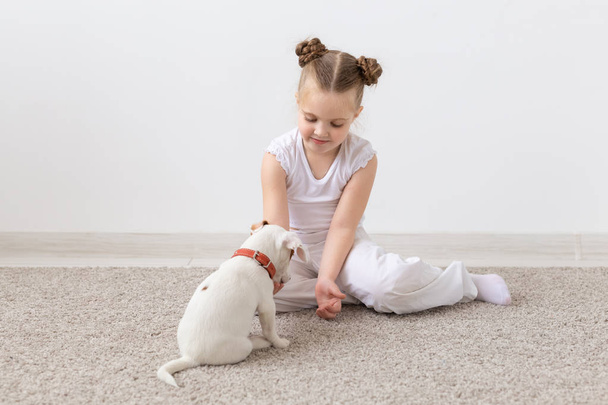 Bambini e concetto animale - Bambina e cucciolo vestiti in pigiama seduti sul pavimento
 - Foto, immagini