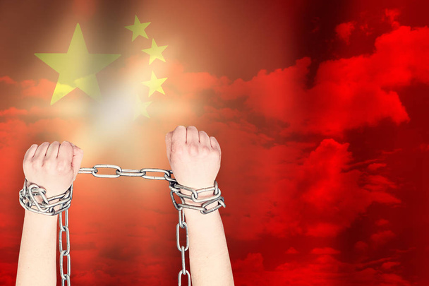 zwei Hände fesselten eine Metallkette auf dem Hintergrund der China-Flagge - Foto, Bild