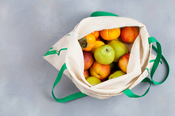 Φρούτα σε επαναχρησιμοποιήσιμα βαμβακερό ύφασμα λευκό τσάντα. Μηδενική αγορά απορριμμάτων, έννοια αποθήκευσης και ανακύκλωσης, φιλική προς το οικολογικό τρόπο ζωής. - Φωτογραφία, εικόνα