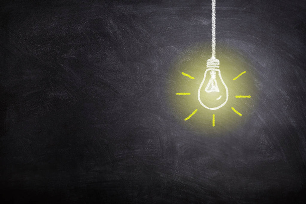 Business Idea Concept : White light bulb lighting grow around on chalkboard. - Photo, Image