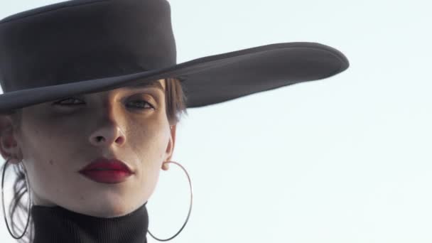 Gyönyörű piros ajkú nő visel fekete kalap néz el elgondolkodva - Felvétel, videó