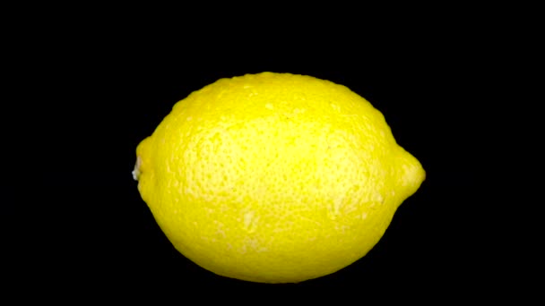 El agua es rociada sobre un limón. Sobre un fondo negro aislado
 - Metraje, vídeo