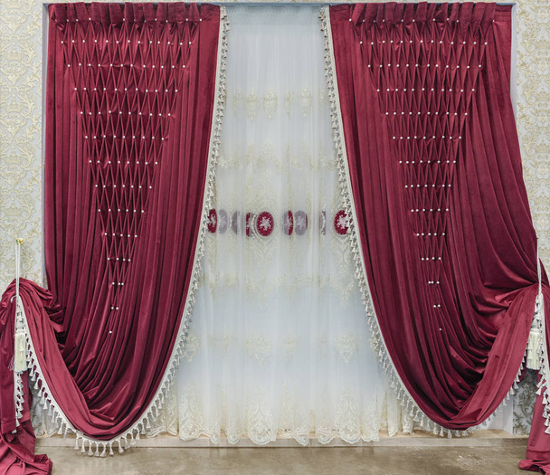 Червоні оксамитові штори з пуфами і білий тюль з вишивкою. Інтер'єр в стилі палацу
 - Фото, зображення