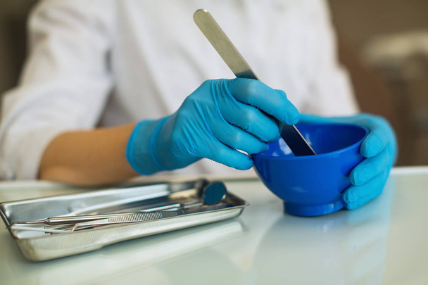 Крупным планом руки женщины-стоматолога доктор месить массу во фляжке
 - Фото, изображение