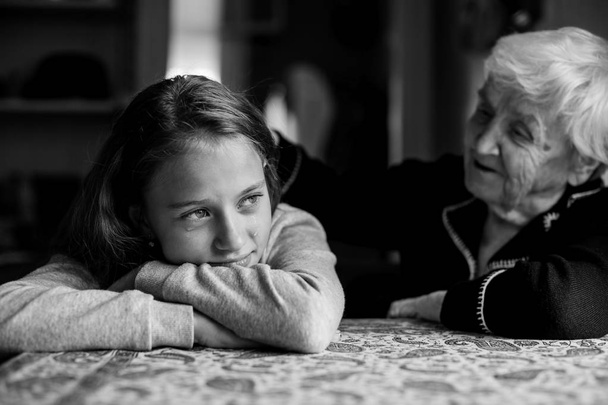 Стара жінка бабуся втішає плачу маленька мила дівчинка онука
. - Фото, зображення