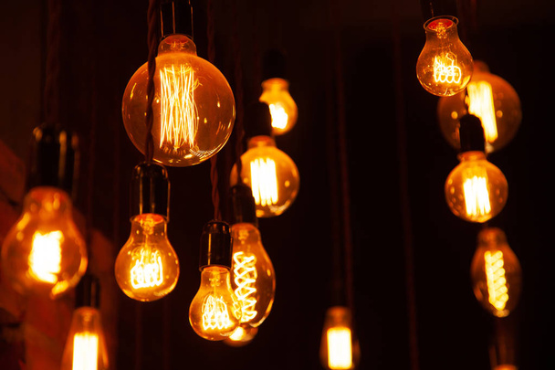 clássico diferentes lâmpadas retro penduradas no fundo da parede de tijolo à noite
 - Foto, Imagem