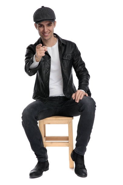 seated casual man resting hand on lap and pointing forward - Φωτογραφία, εικόνα