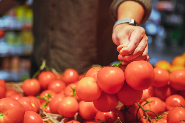 mies käsi valita punaisia tomaatteja ruokakaupassa
 - Valokuva, kuva