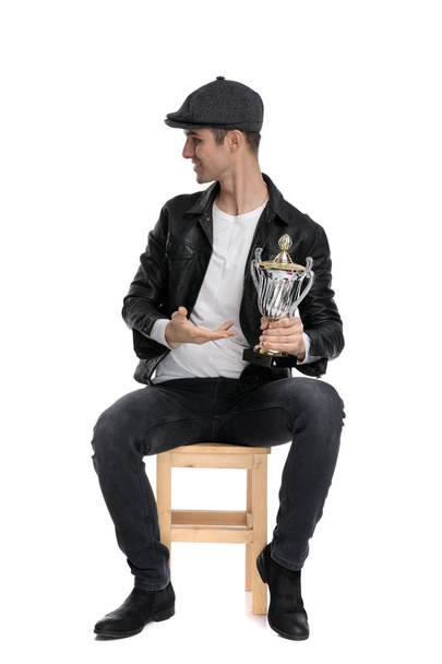 seated casual man presenting his cup and looking sideways - Fotoğraf, Görsel