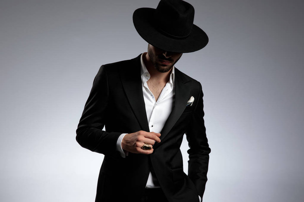 mysteriöser junger eleganter Mann mit Smoking und schwarzem Hut - Foto, Bild