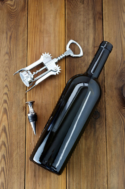 A bottle of wine with corckscrew, wooden rustic background. Flat lay wine drink with copy space. - Foto, imagen