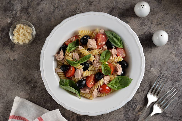 Salad with canned tuna, pasta, cherry tomatoes, olives, parmesan, olive oil and basil. Top view.  - Photo, Image