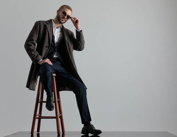 επιχειρηματίας καθισμένος με ένα πόδι να αναπαύεται και να φτιάχνει γυαλιά ηλίου - Φωτογραφία, εικόνα