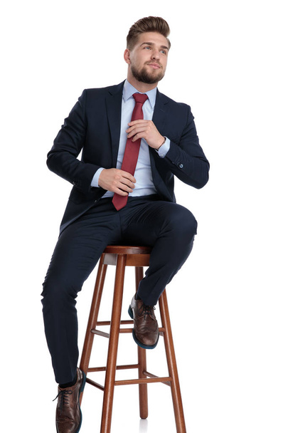 confiante jovem empresário organizando gravata no fundo branco
 - Foto, Imagem