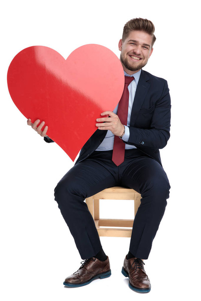 happy young businessman holding red heart in studio - Фото, изображение