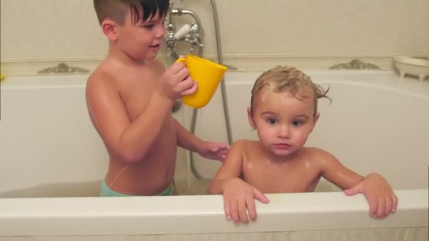 Litttle boy washing his younger brother in a bath - Imágenes, Vídeo