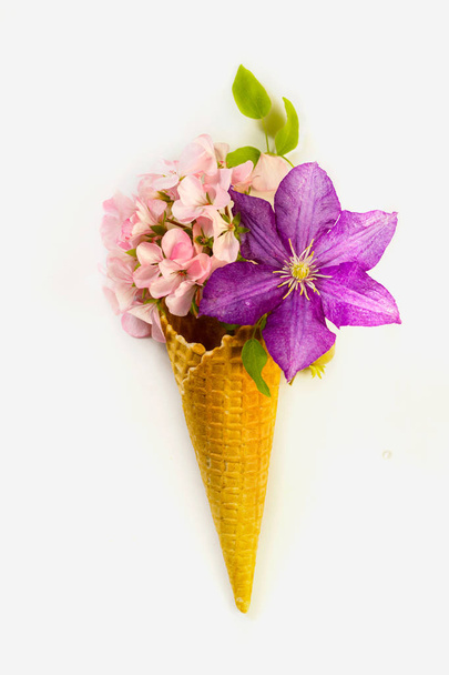 Waffle cone with one beautiful lilac clematis and pink pelargonium and roses with leaves - Foto, Imagem