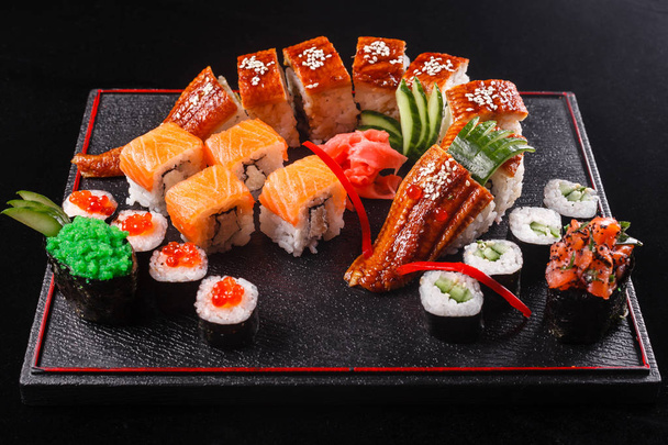 寿司うなぎ、キュウリとアボカド、黒の背景を持つドラゴン。お昼の食事のおいしい日本食 - 写真・画像