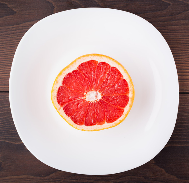 Slice of grapefruit on a palte - Фото, изображение