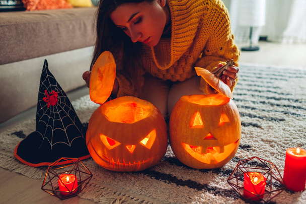 Halloween jack-o-lantern pumpkins. Woman opens pumpkins and looks inside at home. Mysterious holiday - Foto, afbeelding