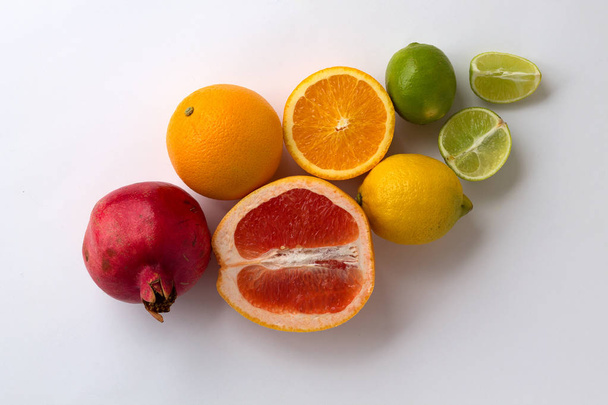 白い背景の上のビューに分離された赤ザクロと新鮮な柑橘系の果物 - 写真・画像