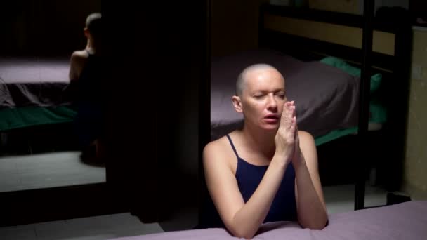 kopasz nő imádkozik térdelve az ágy a hálószobában. másolási tér - Felvétel, videó