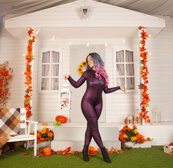 симпатичная женщина на Хэллоуин в обтягивающем тигровом костюме готова праздновать и ждет друзей на вечеринке под открытым небом
 - Фото, изображение