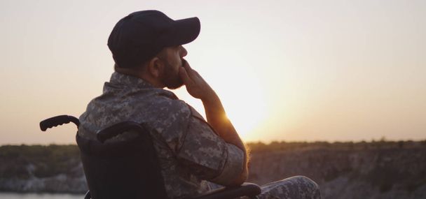 Soldat assis dans un fauteuil roulant sur une prairie
 - Photo, image