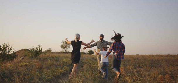 Soldado y su familia caminando en un prado
 - Foto, Imagen
