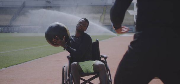 Wheelchaired athlete and trainer throwing medicine ball - Foto, Bild