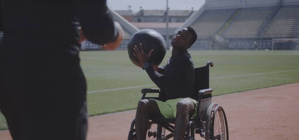 Atleta con ruedas y entrenador lanzando balón medicinal
 - Foto, imagen