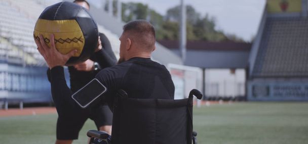 Pyörätuoli urheilija ja kouluttaja heittää lääkepallo
 - Valokuva, kuva