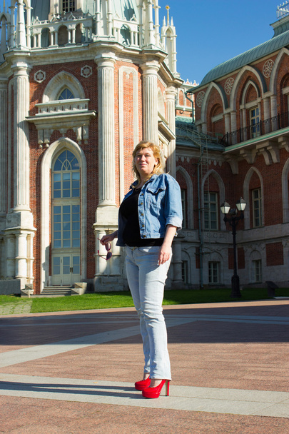 A woman in a blue jacket walking near the Tsaritsyno palace in t - Photo, Image