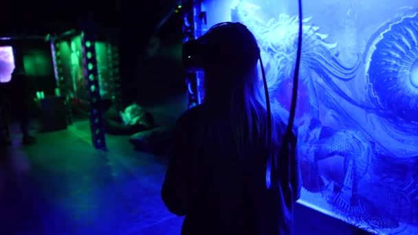 Woman in virtual reality headset against picture on a wall in blue light - Πλάνα, βίντεο